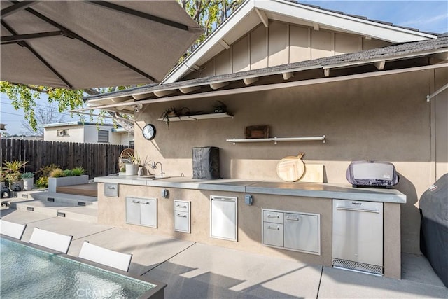 view of patio featuring sink, a fenced in pool, and exterior kitchen