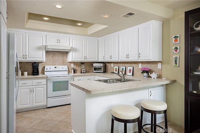 kitchen with white electric stove, white cabinetry, tile countertops, and kitchen peninsula