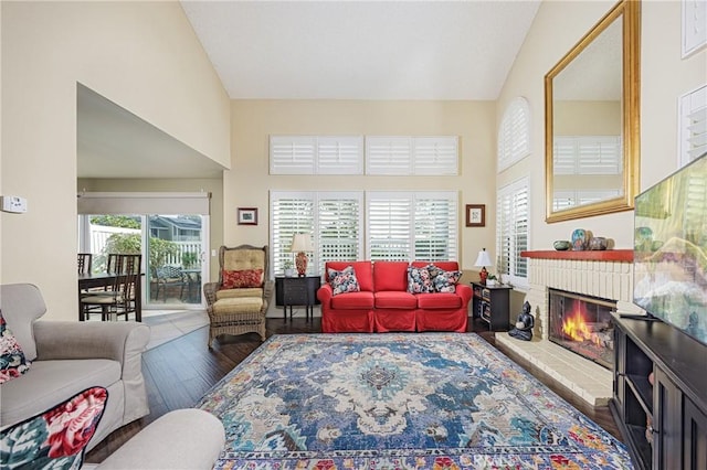 living room featuring dark hardwood / wood-style flooring, high vaulted ceiling, and a brick fireplace