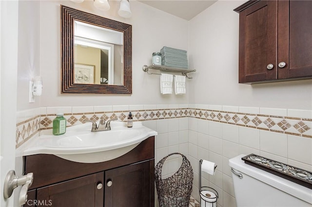 bathroom with vanity, toilet, and tile walls