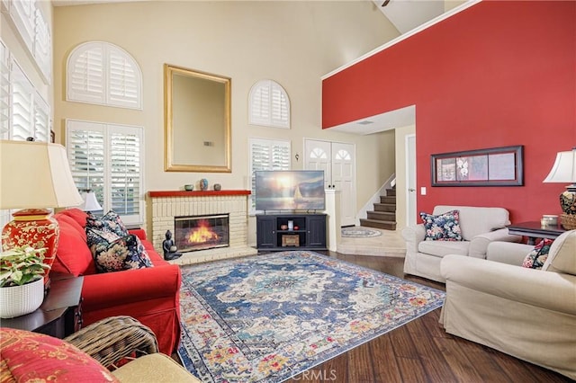 living room with hardwood / wood-style flooring, a towering ceiling, and a fireplace