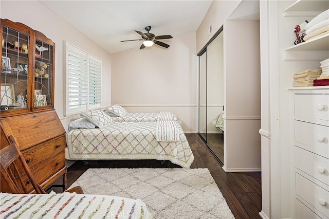 bedroom with dark wood-type flooring, ceiling fan, and a closet