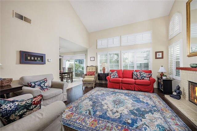 living room featuring a brick fireplace, high vaulted ceiling, and hardwood / wood-style floors