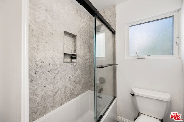 bathroom featuring shower / bath combination with glass door and toilet