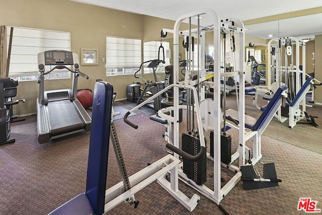 gym with a wealth of natural light and dark carpet