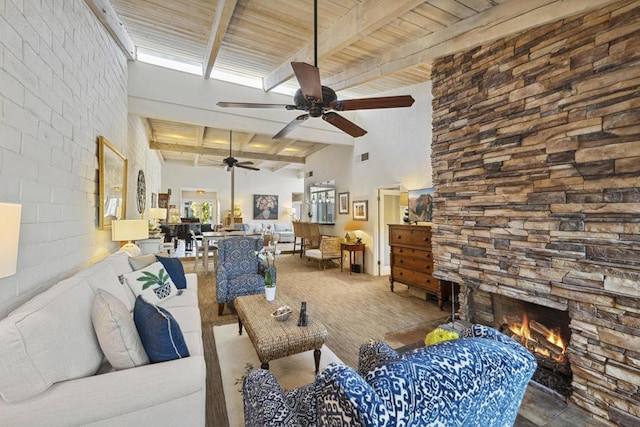 living room featuring ceiling fan, a towering ceiling, beam ceiling, a stone fireplace, and wooden ceiling