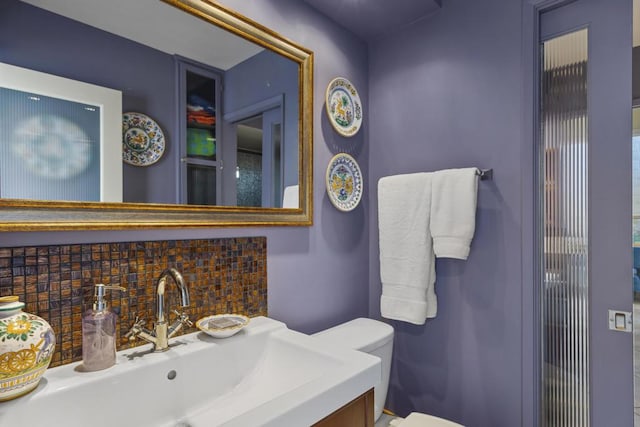 bathroom featuring decorative backsplash, sink, and toilet