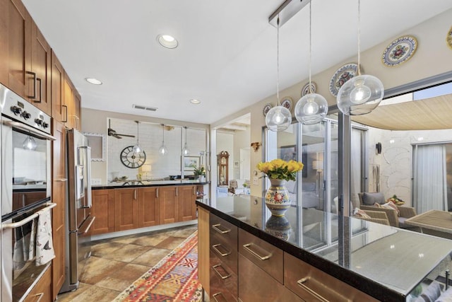 kitchen featuring stainless steel appliances, dark stone countertops, decorative backsplash, and decorative light fixtures