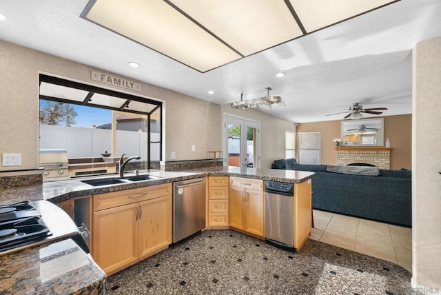 kitchen with a fireplace, dishwasher, sink, kitchen peninsula, and light brown cabinets