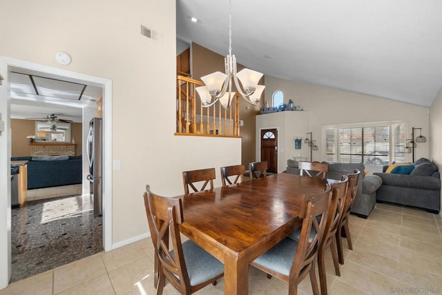 tiled dining space featuring ceiling fan with notable chandelier and high vaulted ceiling