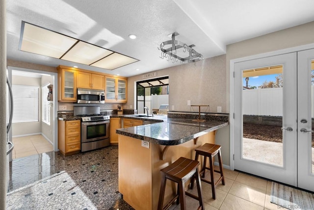 kitchen featuring kitchen peninsula, french doors, a kitchen bar, and stainless steel appliances