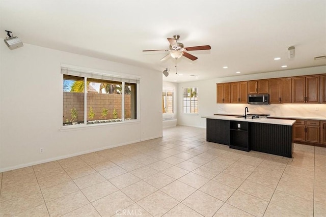 kitchen featuring light tile patterned flooring, ceiling fan, sink, and a center island with sink