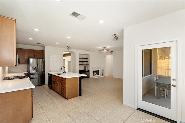 kitchen featuring ceiling fan, stainless steel appliances, sink, and an island with sink