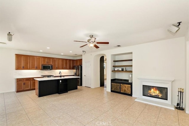 kitchen featuring sink, ceiling fan, range, refrigerator, and an island with sink