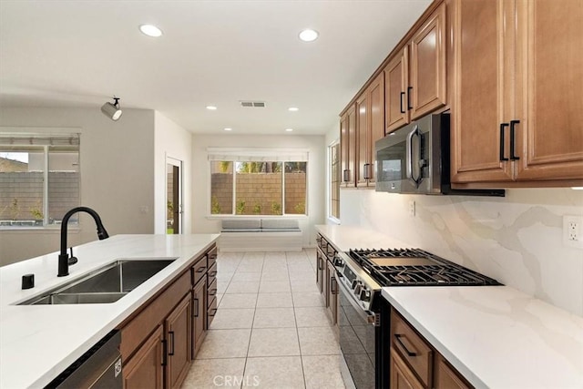 kitchen with appliances with stainless steel finishes, sink, light tile patterned floors, and decorative backsplash