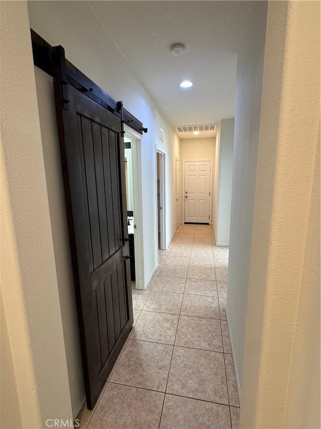 hallway with a barn door and light tile patterned floors