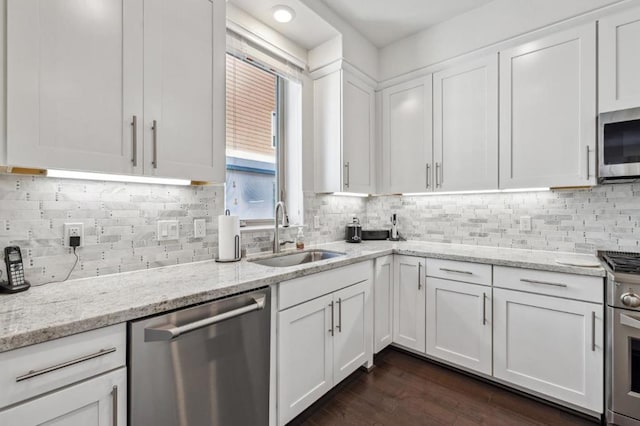 kitchen featuring white cabinetry, sink, dark hardwood / wood-style flooring, light stone counters, and stainless steel appliances