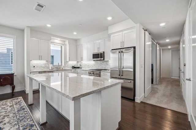 kitchen featuring white cabinetry, light stone countertops, a center island, and high quality appliances