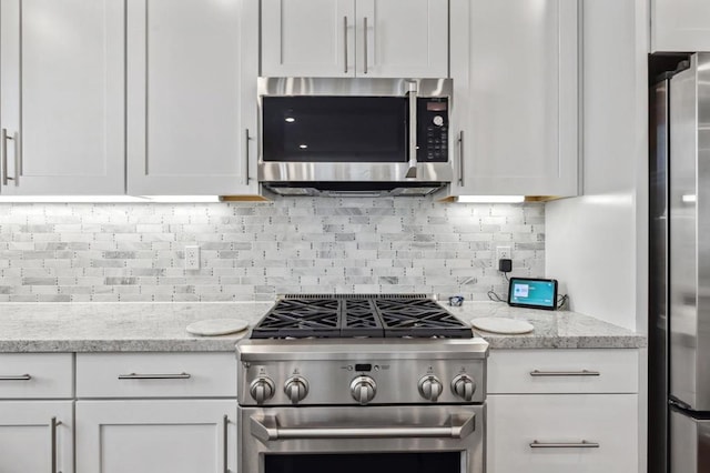 kitchen with appliances with stainless steel finishes, light stone countertops, decorative backsplash, and white cabinets