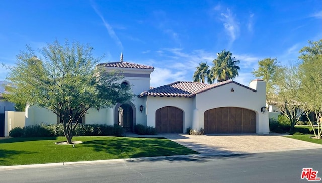 mediterranean / spanish house with a garage and a front lawn