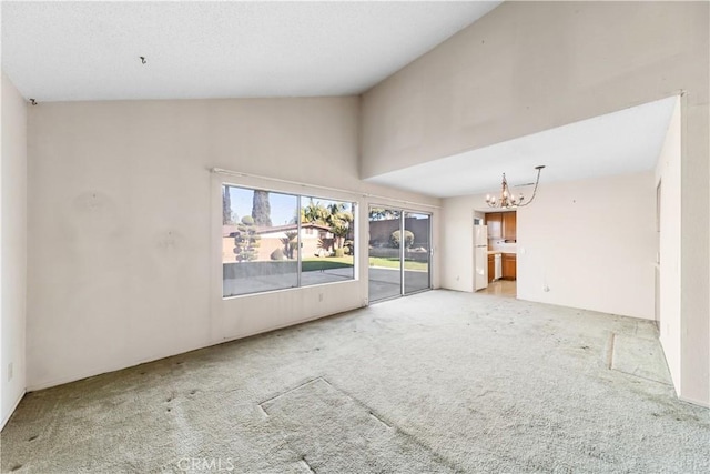 unfurnished living room featuring an inviting chandelier, light colored carpet, and high vaulted ceiling