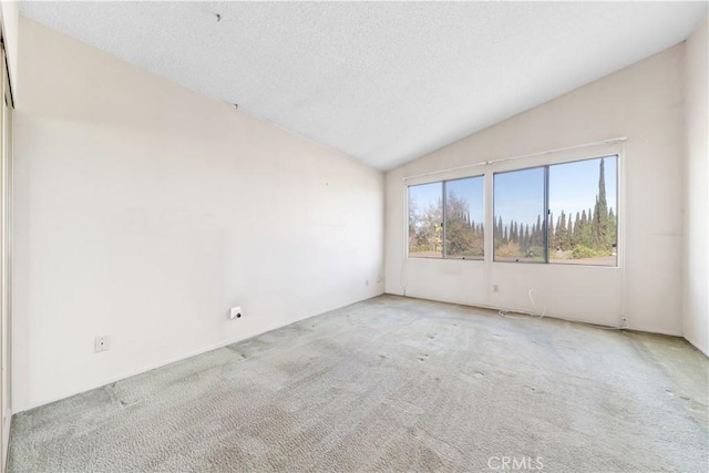 carpeted empty room with a textured ceiling and vaulted ceiling