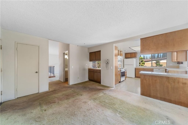 kitchen featuring stainless steel range oven, white refrigerator, a textured ceiling, and light colored carpet