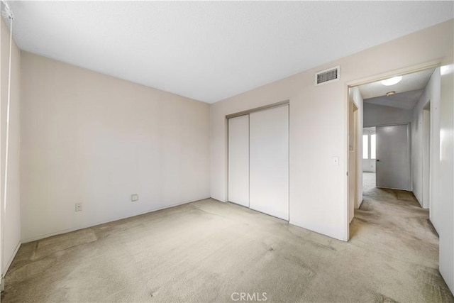 unfurnished bedroom featuring light colored carpet and a closet