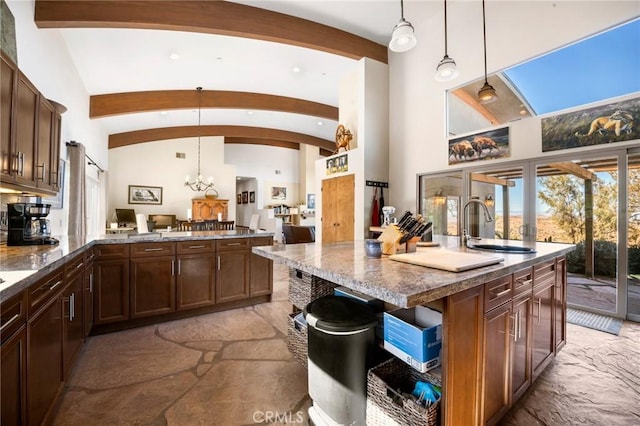 kitchen with sink, decorative light fixtures, a center island with sink, and lofted ceiling