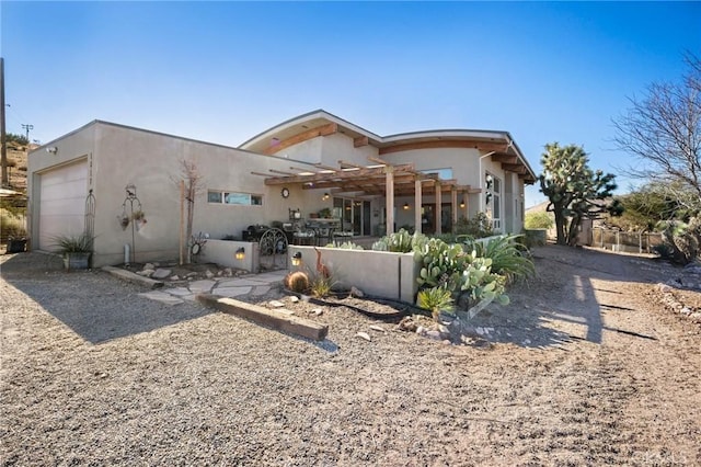 back of property with a garage and a pergola