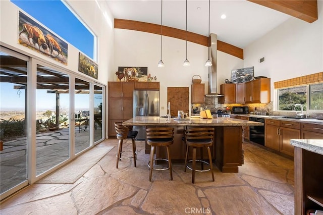 kitchen with black appliances, decorative backsplash, a kitchen breakfast bar, decorative light fixtures, and an island with sink