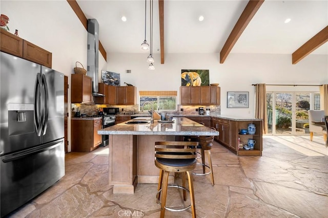 kitchen with pendant lighting, beamed ceiling, black fridge with ice dispenser, a breakfast bar, and a center island with sink