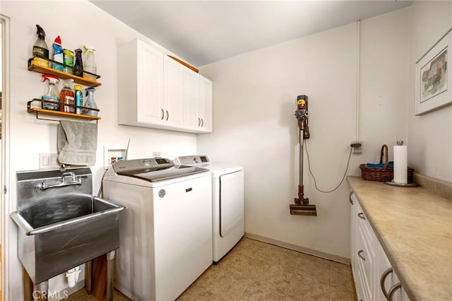 clothes washing area featuring sink, cabinets, and separate washer and dryer