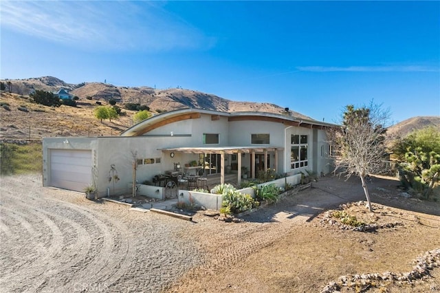 rear view of house with a garage, a patio area, and a mountain view