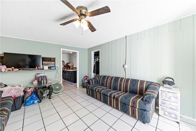 living room with ceiling fan, light tile patterned floors, and a textured ceiling