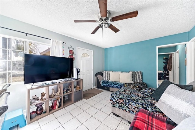 living room with ceiling fan, light tile patterned floors, and a textured ceiling