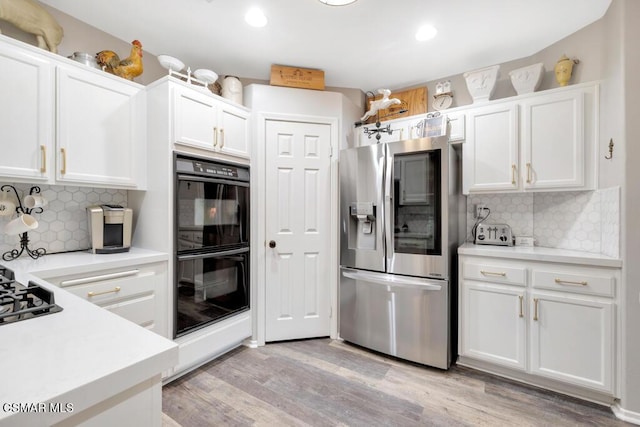 kitchen with white cabinets, tasteful backsplash, stainless steel fridge with ice dispenser, and double oven