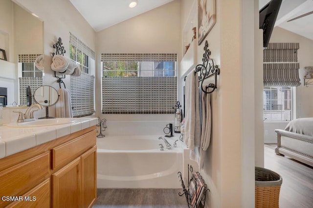 bathroom featuring hardwood / wood-style floors, vanity, a bathing tub, and vaulted ceiling