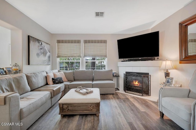 living room with hardwood / wood-style floors and a tiled fireplace