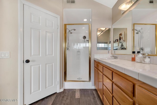 bathroom with hardwood / wood-style flooring, vaulted ceiling, walk in shower, and vanity