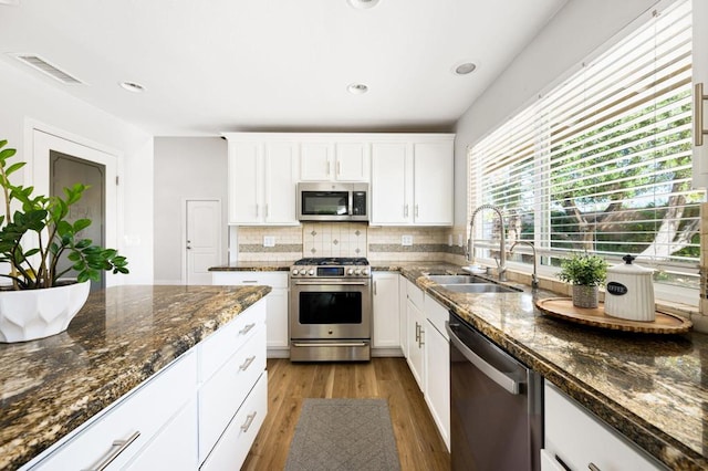 kitchen featuring sink, white cabinetry, dark stone countertops, and stainless steel appliances