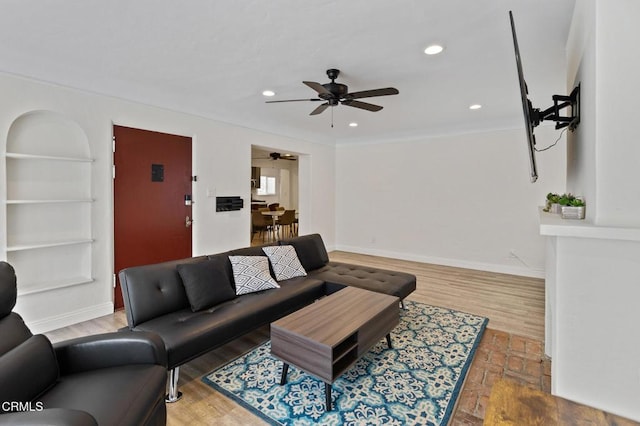 living area featuring a ceiling fan, baseboards, recessed lighting, and built in shelves