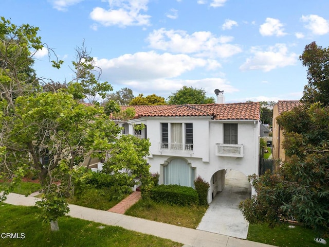 mediterranean / spanish home featuring a chimney, a tile roof, and stucco siding