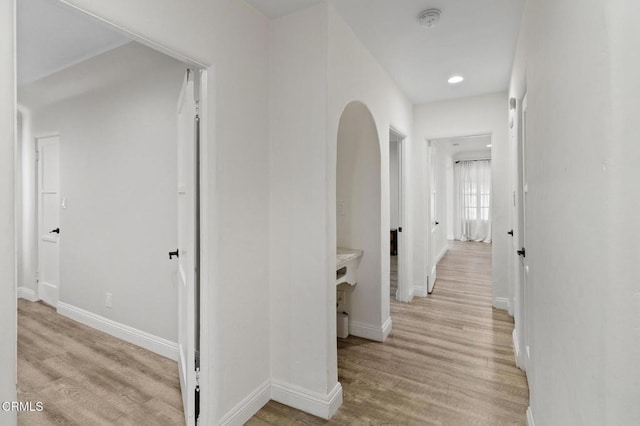 corridor featuring baseboards, recessed lighting, and light wood-style flooring