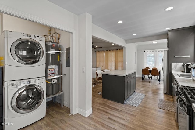 washroom featuring laundry area, stacked washer / drying machine, baseboards, water heater, and recessed lighting