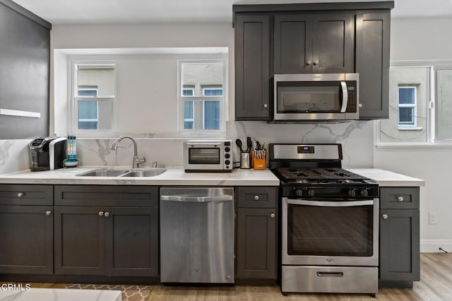 kitchen featuring light countertops, appliances with stainless steel finishes, a sink, and a toaster