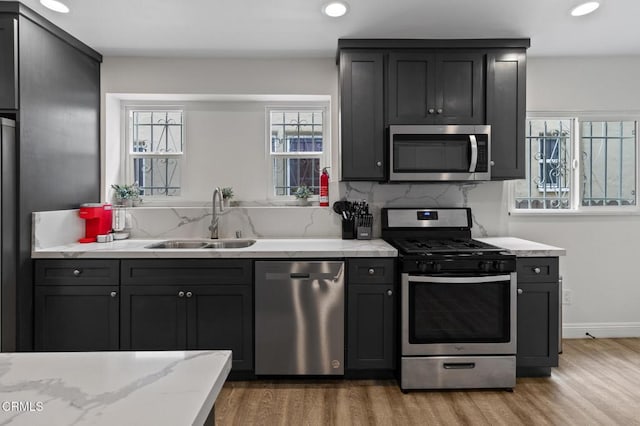 kitchen with a sink, tasteful backsplash, stainless steel appliances, and light wood-type flooring
