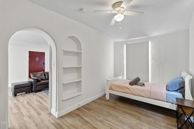 bedroom with arched walkways, baseboards, ceiling fan, and wood finished floors
