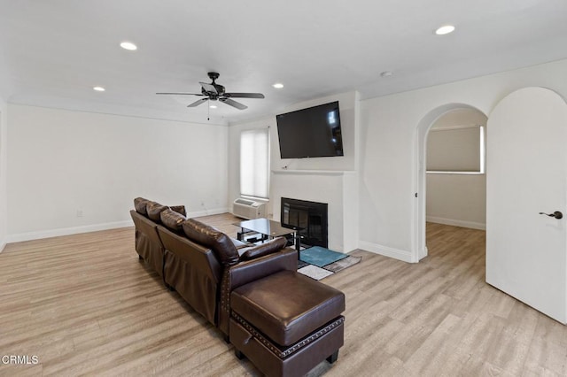 living area with light wood-type flooring, recessed lighting, ceiling fan, and arched walkways