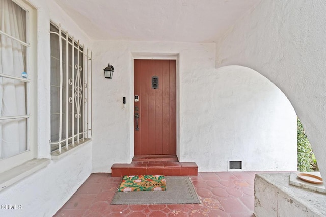 doorway to property featuring visible vents, stucco siding, elevator, and crawl space